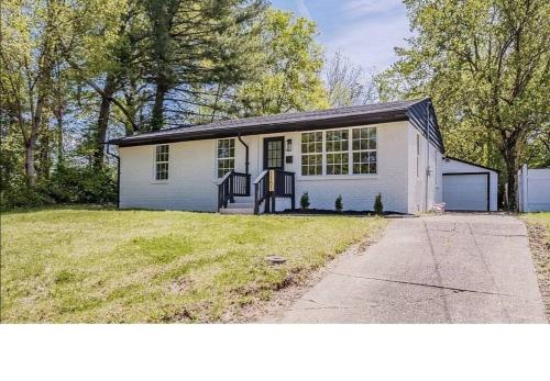 a white house with a garage and a driveway at Game Room and Huge Yard with Fire Pit Yard Games and BBQ Near UE and Downtown in Evansville