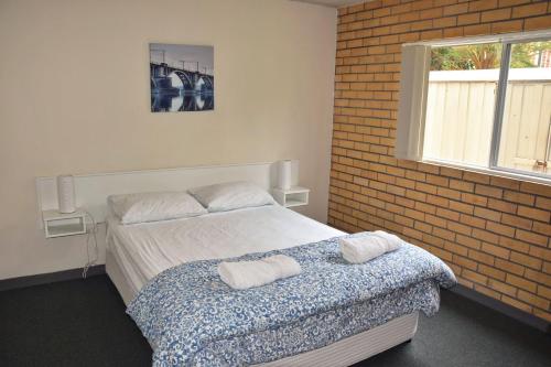 Un dormitorio con una cama y una pared de ladrillo. en Wards Holiday Flat 2, en South West Rocks
