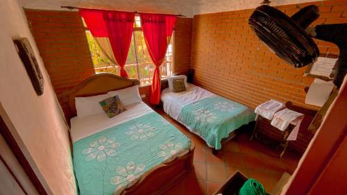 a small room with two beds and a window at La Liliana Hostal - Gastrobar in Jagua