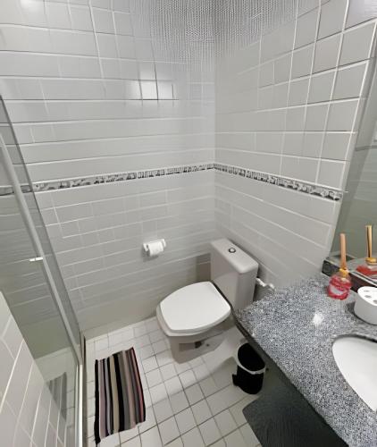 a white bathroom with a toilet and a sink at Casa da Lua Centro in Búzios