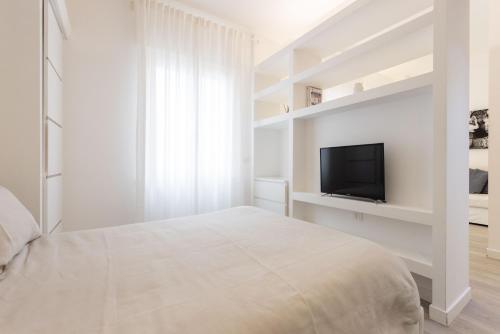 a white bedroom with a bed and a flat screen tv at Palermo ai Leoni in Palermo