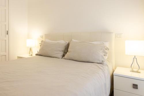 a white bed with white pillows and two lamps at Palermo ai Leoni in Palermo