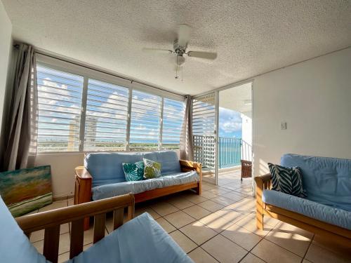 ルキリョにあるBeachfront condo at Costa Azulのリビングルーム(青いソファ、大きな窓付)
