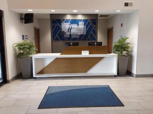 an office lobby with a reception desk with two plants at Holiday Inn Express Hotel & Suites Antigo by IHG in Antigo