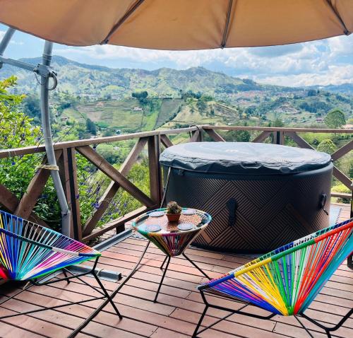 a table and chairs on a deck with an umbrella at Eco Lodge Glamping in Guatapé