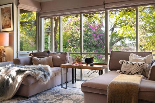 a living room with a couch and a table and windows at The Acorn -open fire,spa bath,dog friendly in Daylesford