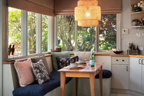 a kitchen with a couch and a table and windows at The Acorn -open fire,spa bath,dog friendly in Daylesford