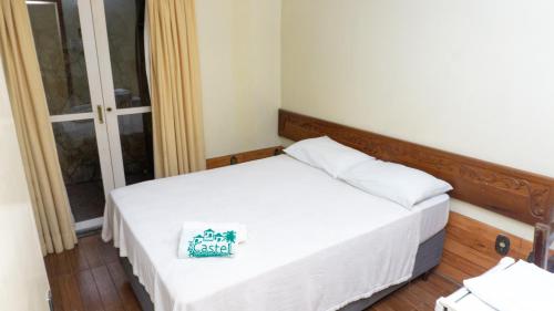 a small bedroom with a white bed and a window at Canoas Hotel Castel in Canoas