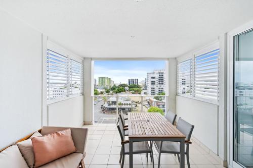 a living room with a table and chairs and a balcony at Belle Escapes 710 Elevated CBD getaway with magical views in Cairns