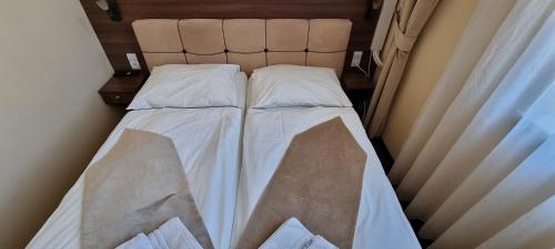 a small bed with white sheets and pillows at Elite Pension in Štúrovo