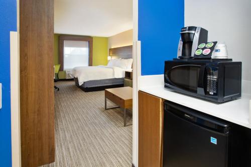 a hotel room with a microwave and a room with a bed at Holiday Inn Express Hotel & Suites Delaware-Columbus Area by IHG in Sunbury