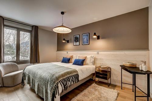 une chambre avec un grand lit et une chaise dans l'établissement White Pearl - Centre de Chamonix - 2ch - Renove, à Chamonix-Mont-Blanc