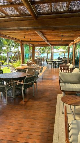 ein Essbereich mit Tischen und Stühlen und eine Terrasse in der Unterkunft Flat Amura Carneiros in Praia dos Carneiros