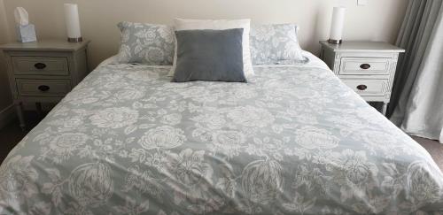 a bed with a gray and white blanket and pillows at Westwood Country House, Studio Apartment, Greytown in Greytown