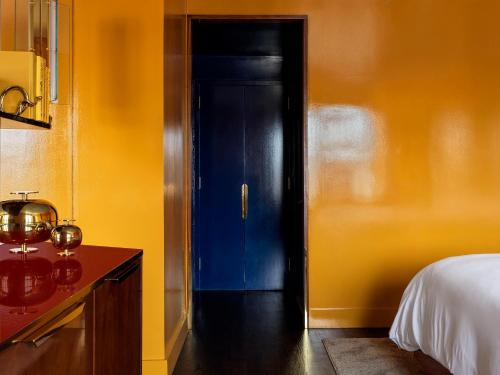 a bedroom with a blue door and yellow walls at The Manner, The Unbound Collection by Hyatt in New York