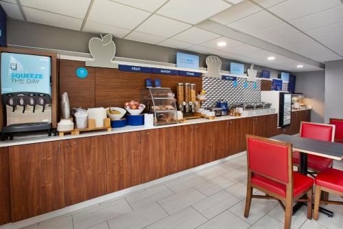 a restaurant with a counter with a table and red chairs at Holiday Inn Express Hotel & Suites Delaware-Columbus Area by IHG in Sunbury