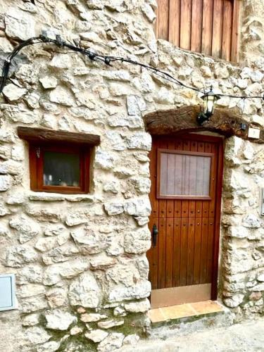 a stone building with a wooden door and a window at Rural Stone House with wood fireplace in Pinell de Bray