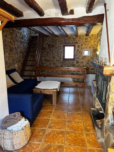 a living room with a blue couch and a fireplace at Rural Stone House with wood fireplace in Pinell de Bray