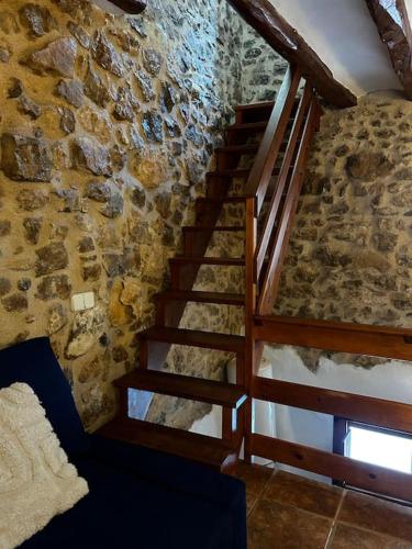 a wooden staircase in a room with a stone wall at Rural Stone House with wood fireplace in Pinell de Bray