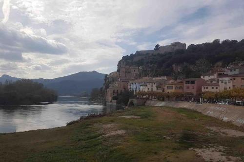 a town on a hill next to a river at Rural Stone House with wood fireplace in Pinell de Bray
