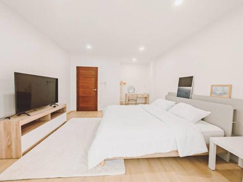 a white bedroom with a large bed and a flat screen tv at Baan-B BangSaen in Ban Bang Saen (1)
