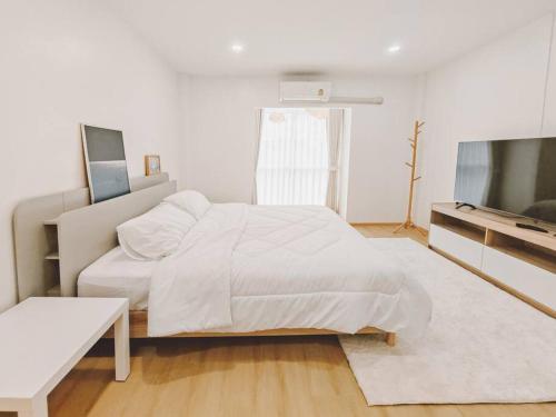 a white bedroom with a bed and a flat screen tv at Baan-B BangSaen in Ban Bang Saen (1)