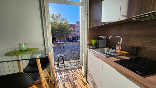Il comprend une cuisine avec un évier et un comptoir avec un balcon. dans l'établissement Le Jardin d'Éden Premium - équipé, balcon, hypercentre, à Toulouse