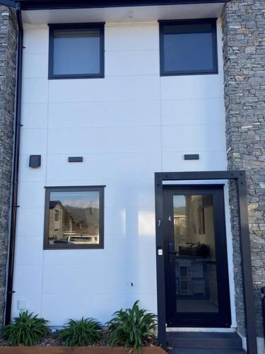 a white building with a black door and two windows at Modern, trendy apartment in Lower Hutt