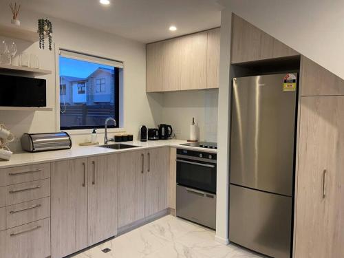 a kitchen with a stainless steel refrigerator and a window at Modern, trendy apartment in Lower Hutt
