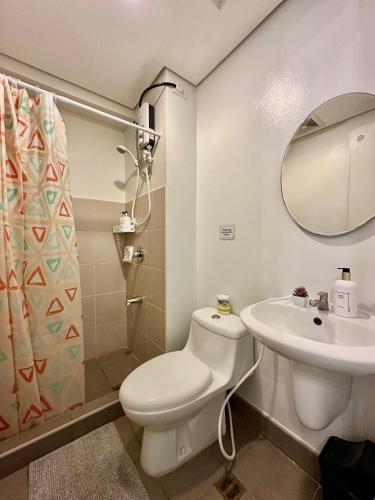 a bathroom with a toilet and a sink and a mirror at Cozy Studio Unit at Centrio Tower beside Ayala Mall Downtown CDO in Cagayan de Oro