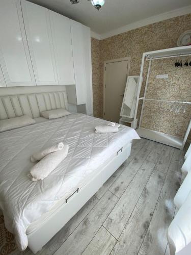 a bedroom with a large white bed with pillows on it at Sweet Villa in Dǝnizkǝnarı Stansiyası