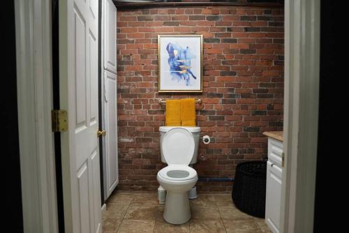 a bathroom with a brick wall and a white toilet at The love loft on the waterfree parking downtown in Troy