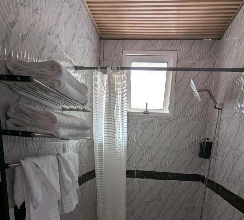 KinshasaにあるL F Suitesのシャワーと白いタオルと窓のあるバスルーム