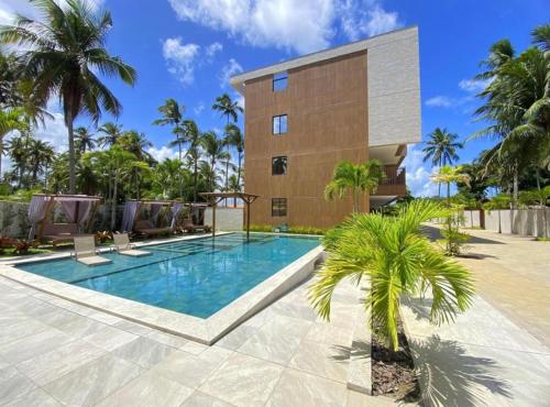 eine Villa mit einem Pool vor einem Gebäude in der Unterkunft Flat Amura Carneiros in Praia dos Carneiros
