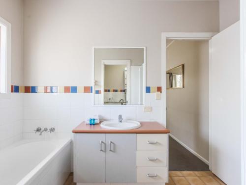 a bathroom with a sink and a tub and a mirror at Hastings Cove Holiday Apartments in Hastings Point