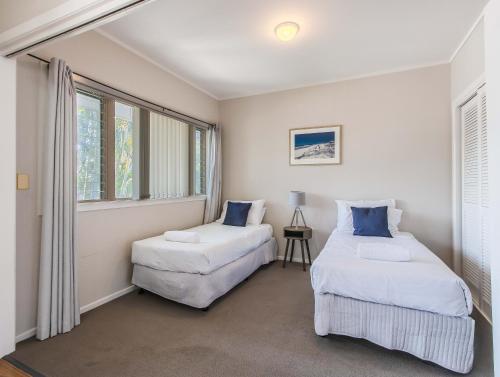 two beds in a room with two windows at Hastings Cove Holiday Apartments in Hastings Point