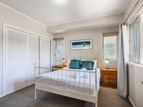 a bedroom with a white bed with blue pillows at Hastings Cove Holiday Apartments in Hastings Point