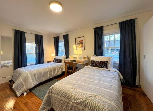 Un dormitorio con dos camas y un escritorio y ventanas. en Quaint Renovated Single Family, en Matawan