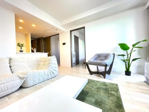 a living room with a white couch and a chair at 902 6名様宿泊可能 札幌中心部 すすきの駅より徒歩5分 ロケーション最高 in Sapporo