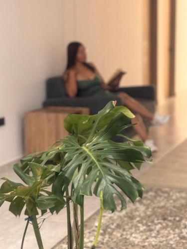 a woman sitting on a couch in a living room with a plant at RB Hotel in Villavicencio