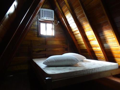 a bed in a wooden room with a window at Chalés Lemes in Anchieta