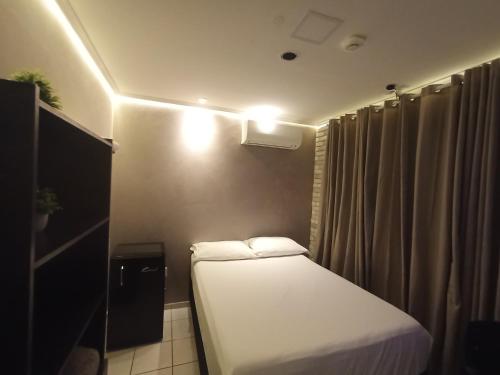 a small room with a bed and a curtain at Praia do Bessa, Caribessa - Quarto Privativo - Conforto, Paz e Sossego, excelente para descansar, trabalhar ou estudar in João Pessoa