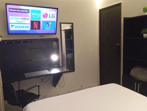 a room with a tv and a bed and a mirror at Praia do Bessa, Caribessa - Quarto Privativo - Conforto, Paz e Sossego, excelente para descansar, trabalhar ou estudar in João Pessoa
