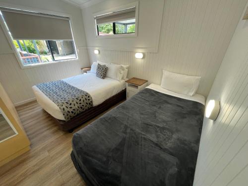 a small bedroom with two beds and two windows at Pyramid Holiday Park in Tweed Heads