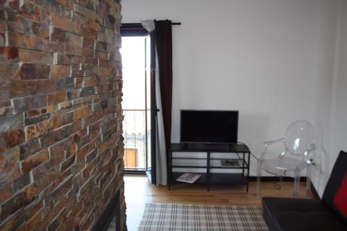 a living room with a brick wall and a tv at Casas do Bairrinho in Sambade