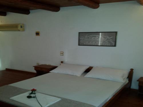 a bedroom with a white bed with a picture on the wall at Kastro Villas in Marathokampos