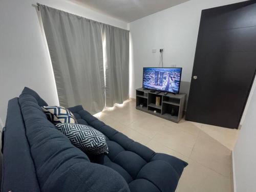 a living room with a blue couch and a television at Alojamiento en León in Santa Gertrudis