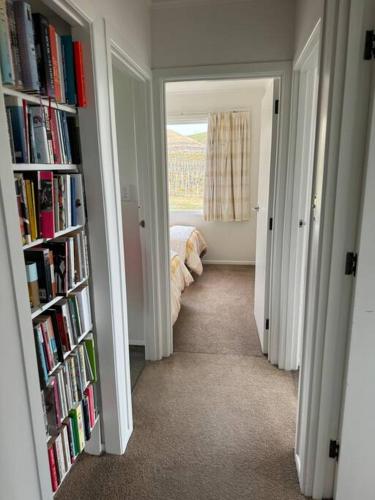 a hallway with two bookshelves and a bed in a bedroom at Three Fifty Cottage in Havelock North