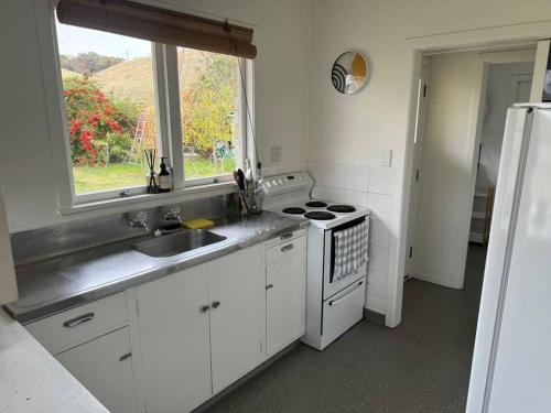 a kitchen with a sink and a stove and a window at Three Fifty Cottage in Havelock North
