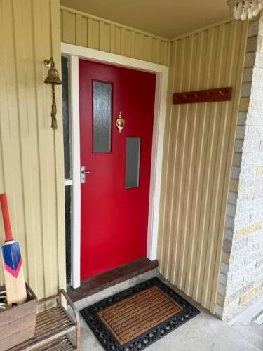 a red door on a house with a bench at Three Fifty Cottage in Havelock North